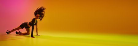 Young talented female dancer performing on stage in hight heels style over gradient pink orange background in neon light. Concept of contemporary dance style, aesthetics, hobby, creativity. bannerの写真素材