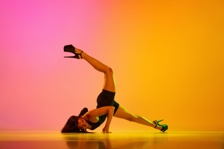 Young beautiful fit woman dancer posing on floor in the style of synch wave in colorful gradient neon light. Concept of contemporary dance style, art, aesthetics, hobby, creativityの写真素材