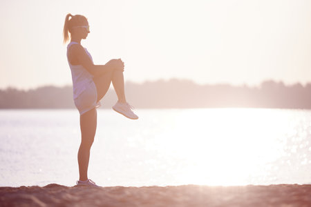 Full length portrait of beautiful sportive girl training at sunrise over seaside. Sportswoman...