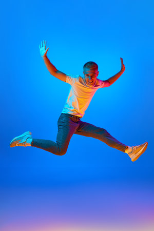 Neon light portrait of victorious delighted jumping man raising hands in star shape, shouting for...