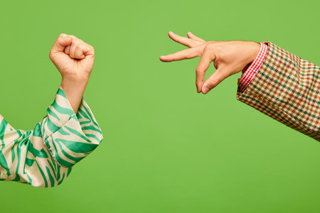 Poster. Two hands, female showing support fist gesture, male demonstrate zero sign isolated on green...