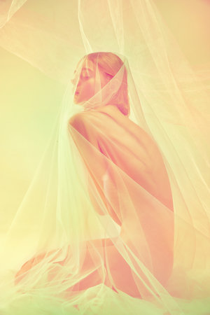 Silhouette of naked tender young girl with slim body shape sitting on floor alone covered wet, transparent fabric. Retro pastel color photo effect. Natural beauty of female body, femininity conceptの写真素材