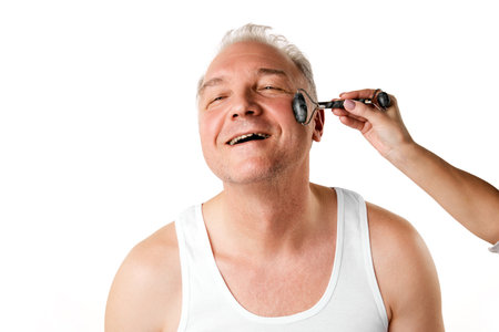 Portrait of confident smiling man 45s dressed white T-shirt with massaging roller isolated beige...
