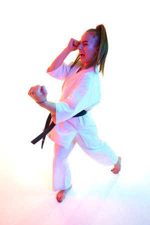 Rear view. Top view portrait of woman professional karate fighter performing kick in action isolated over white background. Concept of sport, recreation, art, hobby, culture. Copy space for ad, text.の写真素材