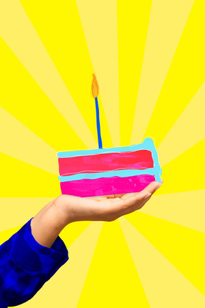 Female hand holding piece of birthday cake with candle over yellow background. Contemporary art...
