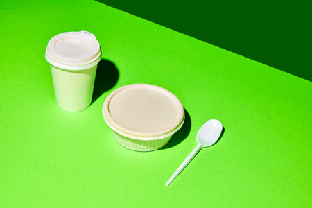 Food packing. Top view of blank white plastic container, cutlery and paper cup for drinks over orange-green background. Concept of fast food, street food, delivery, menu, catering. Copy space for ad.の写真素材