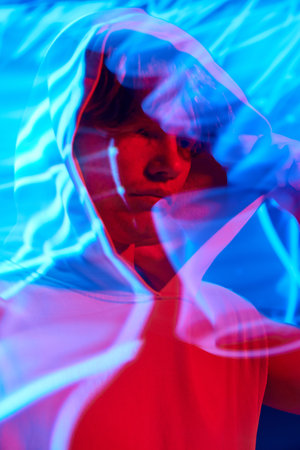 Portrait with long exposure. Young man, calm guy posing in futuristic digital projector reflection and in vivid neon light. Concept of beauty, self-expression, emotions, fashion, techno, style. Adの写真素材