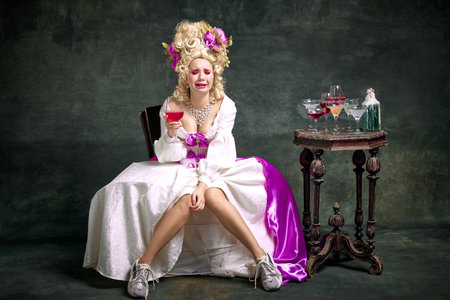Upset, crying in despair queen, medieval person in old-fashioned dress and modern shoes sitting...