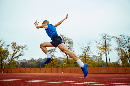 Dynamic steps leading to an impactful long jump. Bottom view full length portrait of professional sportsman running on sport field. Concept of kinds of sport, championship, motivation, energy.の写真素材