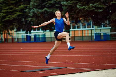 Picture-perfect technique on display as sportsman executes jump. Athletic man, professional sportsman sets new long jump record. Concept of kinds of sport, championship, motivation, energy.の写真素材