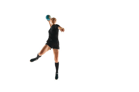 Fit, focused woman engaged in handball drills, displaying determination and focus against white studio background. Concept of sport, hobby, movement, dynamic, active lifestyle, workout, championship.の写真素材