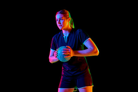 Portrait of focused woman, handball player holding ball to make perfect precise serve early in game against black background in neon light, filter. Concept of professional sport, championship 2024. Adの写真素材