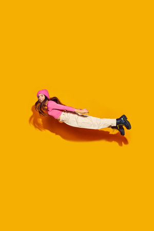 High-flying style. Fashion-forward young girl jumps in modern, comfortable clothing against vibrant yellow background. Concept of fashion and beauty, modern style, movement, shopping, sales.の写真素材