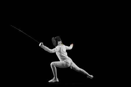 Fencers footwork and poised stance in mid-bout against pristine black studio background. Tactical aspect dynamic sport. Concept of professional sport, active and healthy lifestyle, championship. Adの写真素材