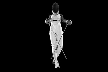 Fierce female fencer, gracefully wielding swords in dynamic pose against white studio background. Strength, agility, and artistry of fencing. Concept of professional sport, active, healthy lifestyle.の写真素材