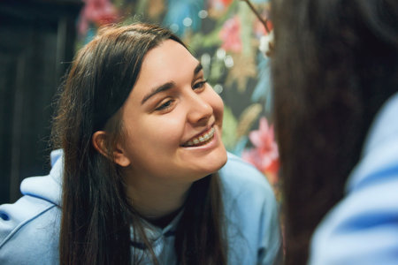 Young adult woman with braces smiling and looking at her perfect smile in bathroom mirror. Casual outfit. Concept of beauty and medicine, hygiene, self care treatment. Adの写真素材