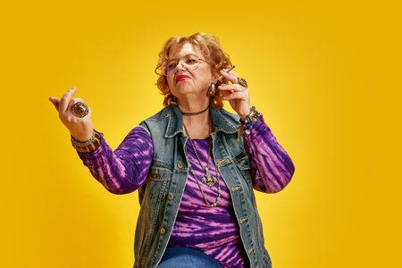 Portrait of directive mature woman dressed retro clothes posing looking away against yellow...