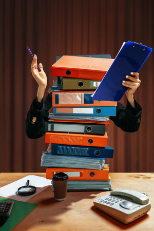 Chaos of poor scheduling. Person with tall stack of colorful binders instead of body, holding clipboard and pen, with office items on desk. Concept of self-expression, work-life balance.の写真素材