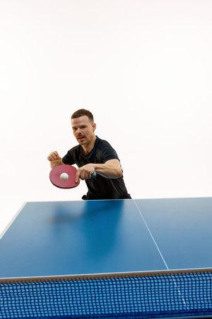 Intense table tennis rally. Dynamic portrait of young man player in motion against white background. Concept of professional sport, championship, tournament, action, power and strength. Copy space.の写真素材