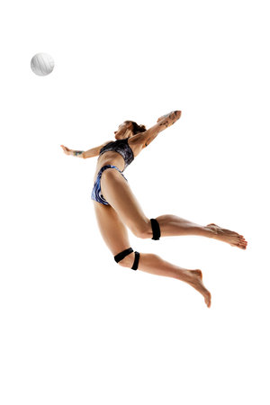 Dynamic portrait of athlete woman, volleyball player hitting ball in motion against white studio background. Concept of sport games, movement, championship, power and strength, action and energy.の写真素材