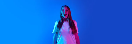 Banner. Young woman shouting of happiness in neon light against gradient background with negative...