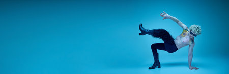 Banner. Young man with naked torso posing standing on hands against blue background with negative...