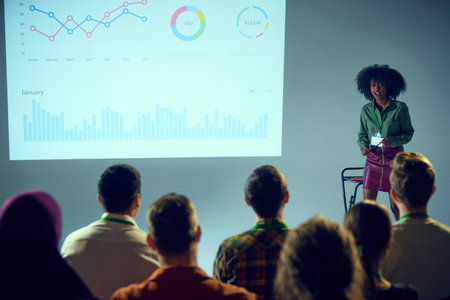 Confident African-American woman, expert with stands in front of audience, giving lecture with data...