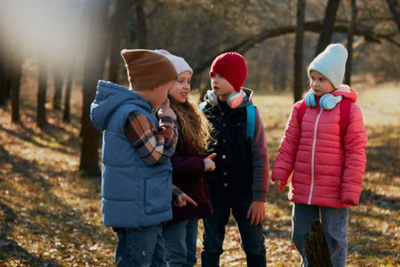 Children, classmates, friends in circle talk and gesture, enveloped in warmth autumn sun. Concept of outdoor activities for childrens development, school, childhood, fashion and style. Adの写真素材