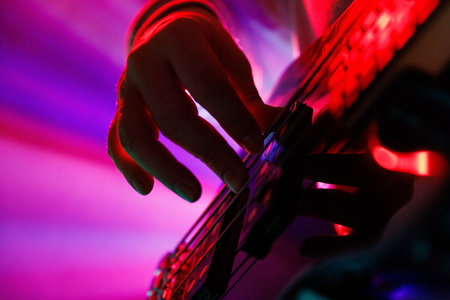 Close up photo of musicians hand on guitar neck with blue backlight and hazy smoke, highlighting musical performance. Concept of rock and classic music, hobby and work, energy, music festivals. Adの写真素材
