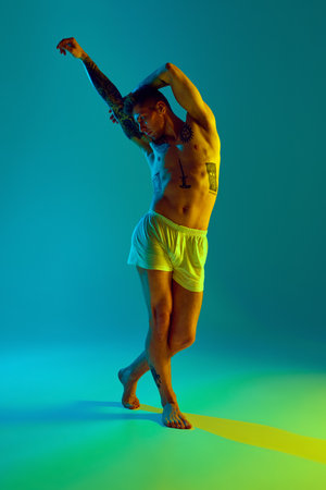Attractive man with muscular, athletic body posing in underwear raising arms in neon light against gradient studio background. Concept of natural beauty, fashion and style, male health, body care. Adの写真素材