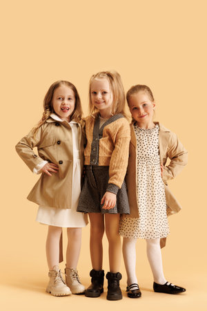 Happy, smiling little girls, elementary pupils posing dressed glamour outfit against beige studio background. Concept of fashion and style, beauty, childhood, Black Friday, Cyber Monday.の写真素材
