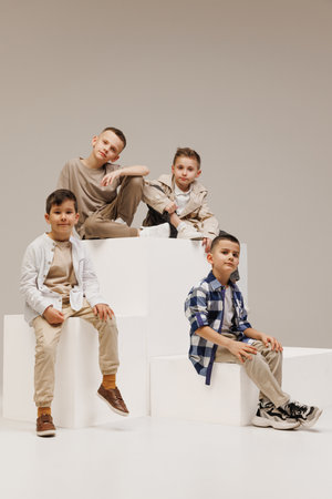 School fashion. Brutal little boys, kids, friends posing in stylish outfits against grey studio background. Concept of childhood, kids fashion and beauty, style, school shopping. Black Friday.の写真素材