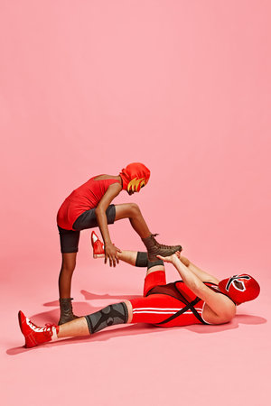 Boy in red costume with mask stands above older man in dominant pose against pink studio background. Concept of pop art, generation difference, costume festivals, competitions. Adの写真素材