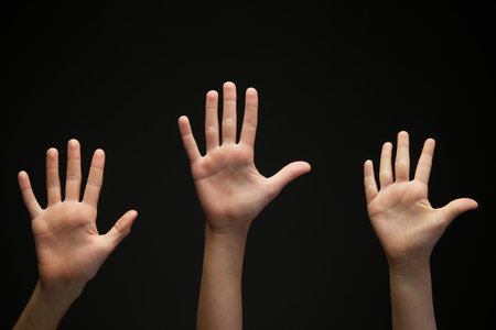 Image of teenagers, childrens hands shows palms against black background. Hands raising up. Concept of youth, expression, beauty, emotions, gestures, art and symbolism, diversity. Adの写真素材
