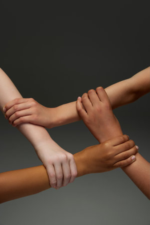 Group of childrens hands holding on to each other, symbolizing work in team and support against dark gradient background. Concept of youth, expression, beauty, emotions, gestures, diversity. Adの写真素材