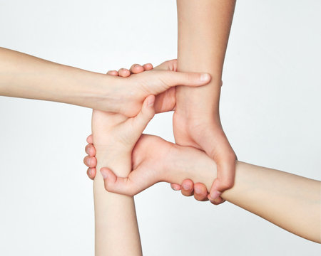 Group of childrens hands holding on to each other, symbolizing work in team and support against grey...