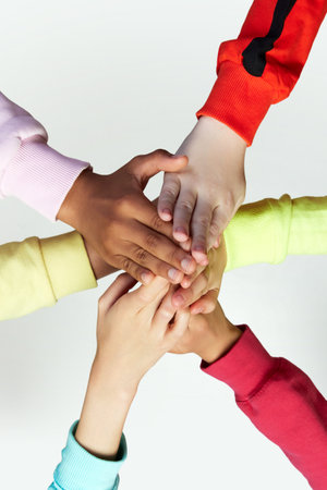 Close up of childrens hands giving a high five in collaboration for mission, goal or team building...