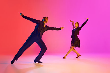 Pair of dancers in elegant poses in neon lighting against gradient background. Couple perform passionate Latin dance.Concept of dance and music, professional sport, action, competition, classical. Adの写真素材