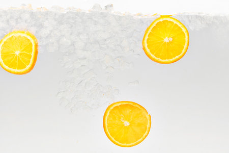 Close up photo of lemonade drink with slices of citrus fruit floating in liquid against white background. Textured photo. Abstract wallpaper. Concept of food and drinks, summer,vitamins, nutrition.の写真素材