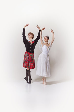 Ballerina in white dress and floral crown and her partner in traditional Scottish kilt and jacket striking matching pose against white studio background. Concept of art, romatic, creativity. Adの写真素材