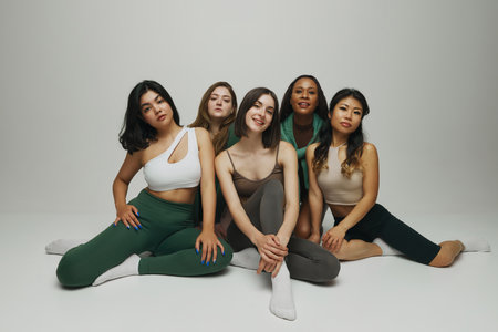 Women, representing range of body types and ethnicities, posing together in chic athletic outfit...