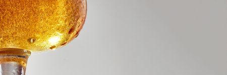 Banner. Close-up of glass filled with cold, golden beer against grey studio background. Condensation droplets on glass. Concept of food and drink, celebration, Oktoberfest, beverage industry. Adの写真素材