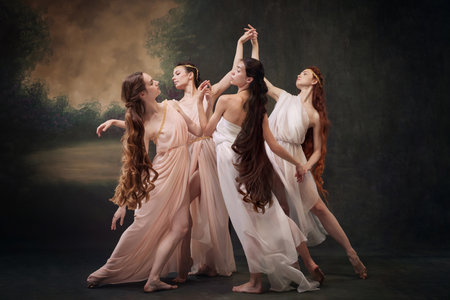 Dance of Muses. Quartet of ballerinas in soft dresses express elegance of classical dance against vintage studio background. Concept of ballet, history, fusion of modernity and ancient times in art.の写真素材