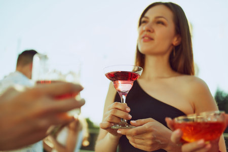 Celebratory vibes fill air as friends clink their glasses, savoring warmth and each others company. Party outdoor. Concept of party, Friday mood, celebration, summer holidays, relax.の写真素材