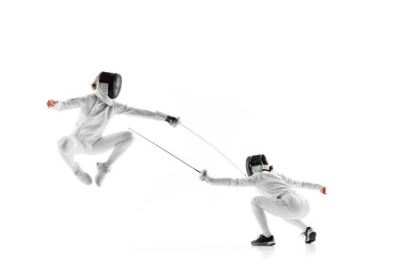 Two young girls, athletes during intense fencing duel, showcasing their skill and agility against...