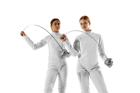 Two female fencers pose confidently with their swords, showcasing their skills and precision against...
