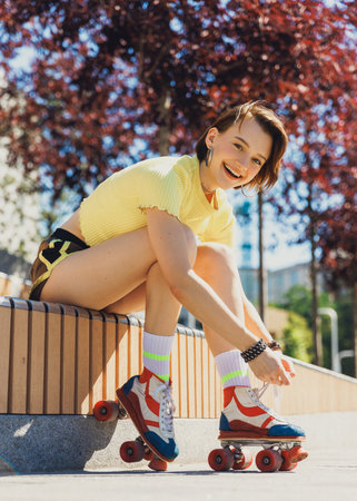 Sportive, happy young girl, teenager ties laces on retro roller skaters, getting ready for training...