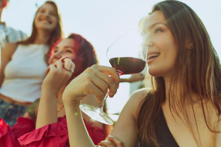 Portrait of festive toast among friends, men and women, their drinks glistening in warm rays of sun. Hot summer holidays. Concept of party, Friday mood, celebration, summer holidays, relax.の写真素材