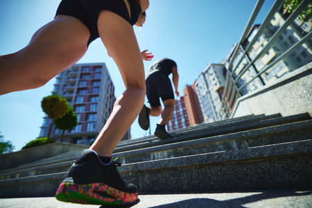 Low angle shot of man and woman running up set of stairs in urban environment. Motion and determination. Movement. Concept of sport and healthy lifestyle, pair training, leisure activity.の写真素材
