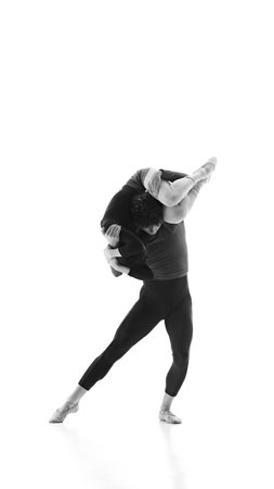 Ballet partners, man and woman harmonize their movements during training against white studio...